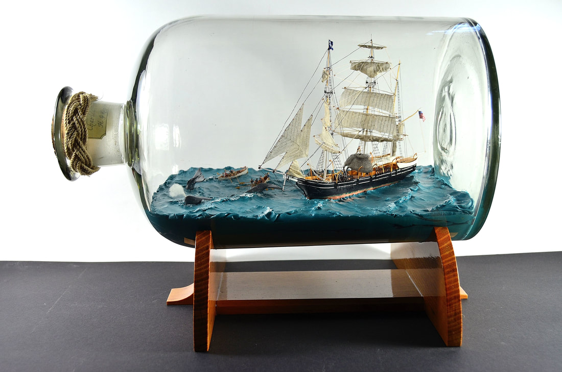 A diorama in a bottle of the whaling ship Charles W. Morgan and her crew hunting a pod of sperm whales
