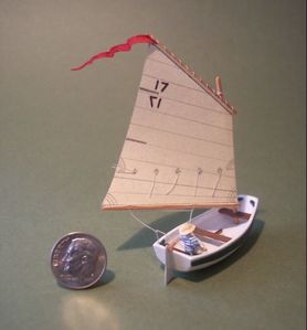 Miniature model of a Nutshell Sailing Pram with a little boy at the helm