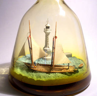 Ship in bottle model of the Barque La Neptune passing the Phare des Paquis.