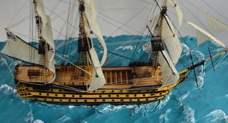 Close-up view of the miniature model of the HMS Victory displaying the deck and cannons.