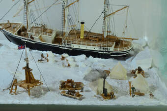 Model diorama of a ship trapped in pack ice and it's crew living in a makeshift camp on the ice.