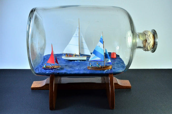 Diorama in a bottle of a Troy, Mirage, and a Fowey River Dinghy approaching a regatta buoy